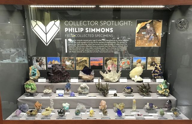 A museum display case showcasing various mineral specimens with a spotlight on collector Philip Simmons.